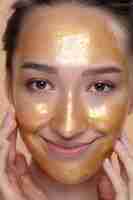 Free photo front view smiley woman with golden face mask