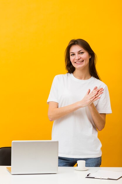 Front view of smiley woman with laptop next to her