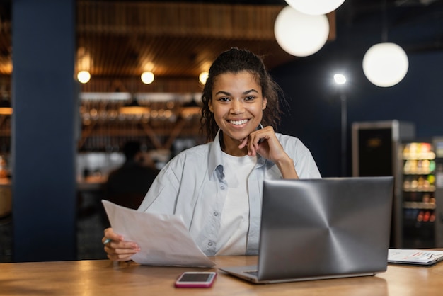 Front view of smiley woman working in the office in front of laptop