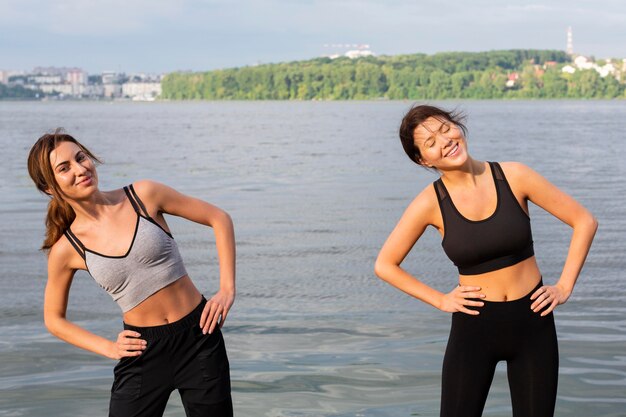 Free photo front view of smiley women exercising together outdoors