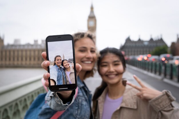 Foto gratuita donne sorridenti di vista frontale con lo smartphone