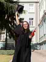 Free photo front view smiley young woman wearing graduation gown