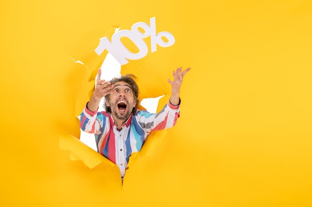 Free photo front view of smiling bearded man playing with ten percentage numbers in a torn hole in yellow paper