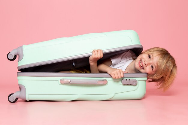 front view smiling blonde boy inside white bag on pink floor