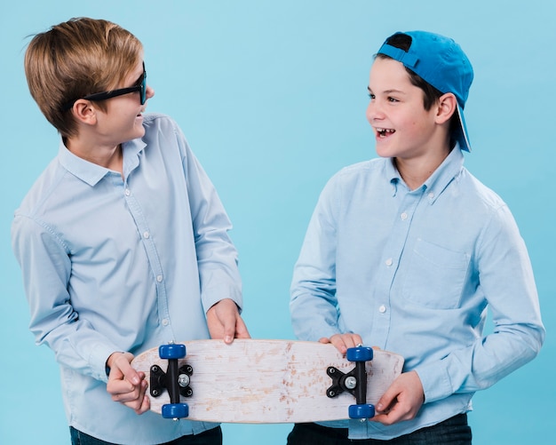 Free photo front view of smiling boys holding a skateboard