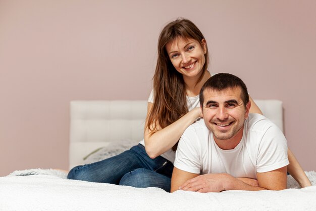 Front view smiling couple sitting in bed