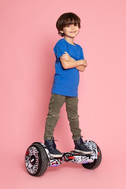 A front view smiling cute boy riding segway on the pink space