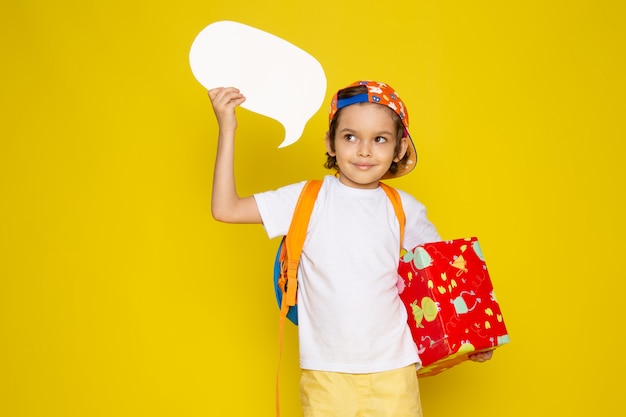 front view smiling cute kid in white t-shirt and baseball cap on yellow floor