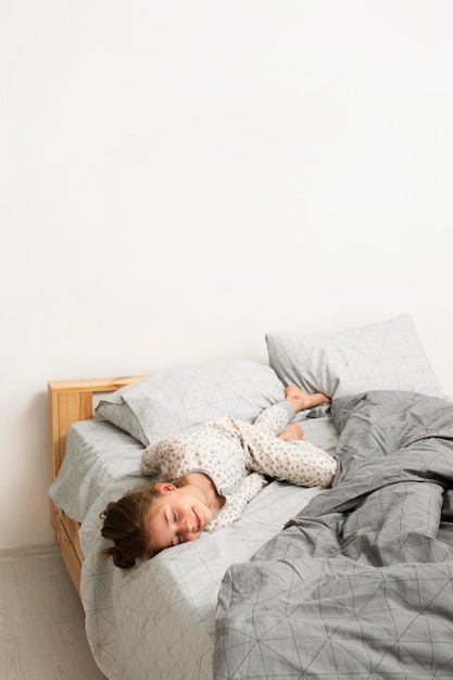 Free photo front view of smiling girl in bed with copy space