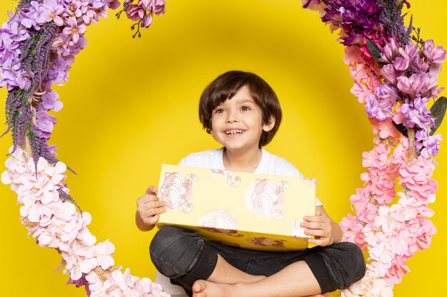 A front view smiling happy boy with painting in white t-shirt on the yellow space