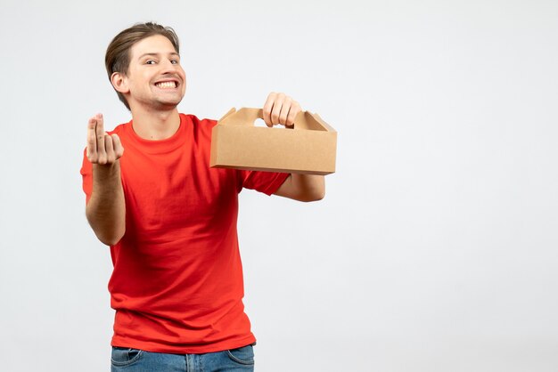 Front view of smiling happy young man in red blouse holding box on white background