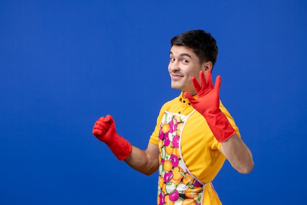 Free photo front view of smiling housekeeper man hailing someone standing on blue wall