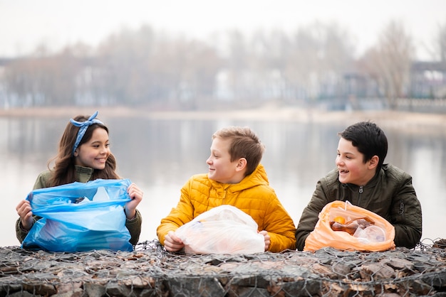 Front view of smiling kids with plastic bags