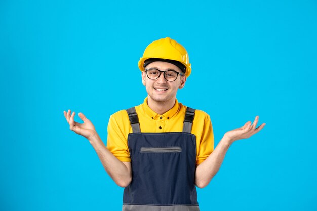 Вид спереди улыбающегося работника мужского пола в униформе и шлеме на синем