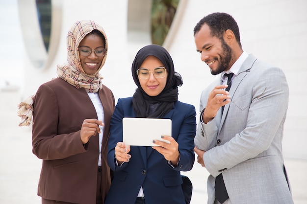 Front view of smiling managers using tablet outdoors