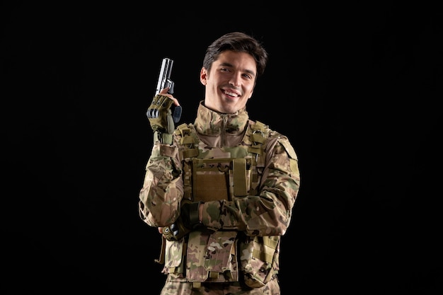 Front view of smiling military serviceman in uniform on black wall