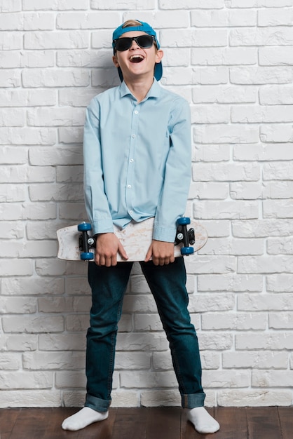 Front view of smiling modern boy with skateboard