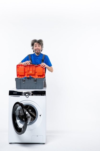 Free photo front view of smiling repairman holding tools bag behind washing machine on white wall