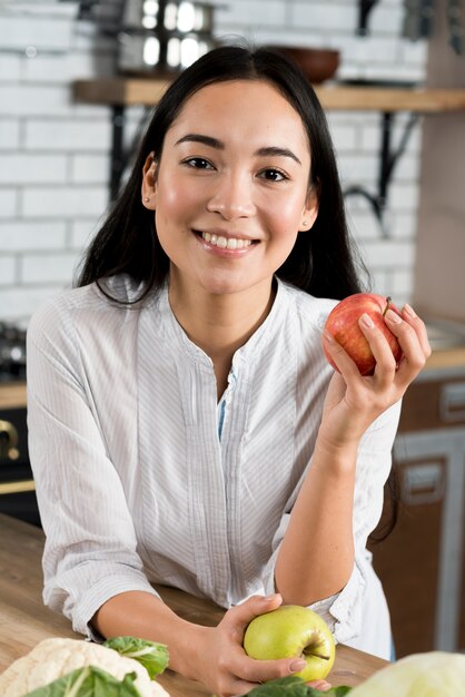 Front view of smiling woman holding apples looking at camera