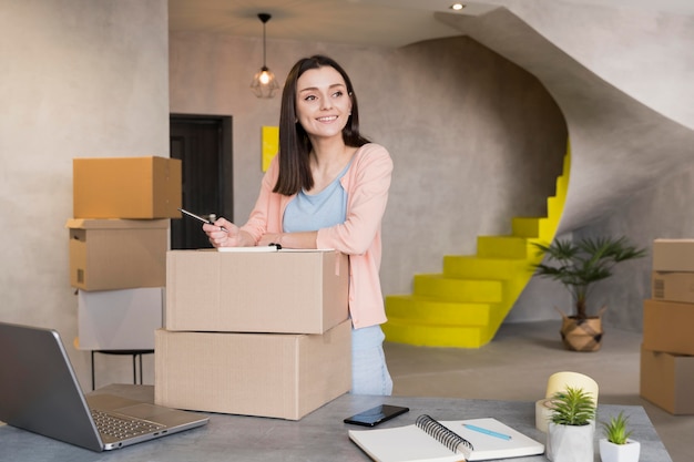 Front view of smiling woman preparing boxes for delivery