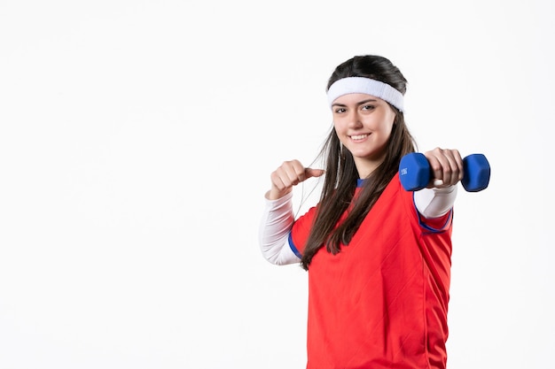 Вид спереди улыбающаяся молодая женщина в спортивной одежде с синими гантелями