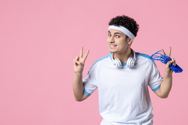 Вид спереди улыбающегося молодого мужчины в спортивной одежде со скакалкой