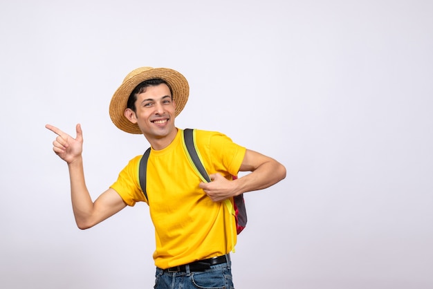 何かを指している赤いリュックサックと黄色のTシャツで若い男を笑顔の正面図