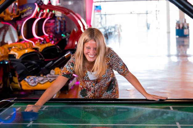 Вид спереди улыбающаяся женщина играет в воздушный хоккей