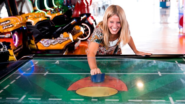 Вид спереди улыбающаяся женщина играет в воздушный хоккей