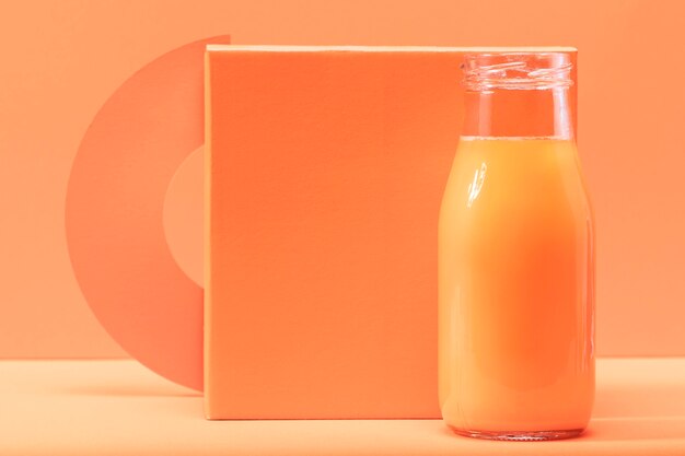 Front view smoothie in bottle in front of orange square