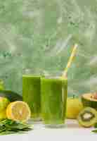 Free photo front view smoothie glasses with lemon and kiwi