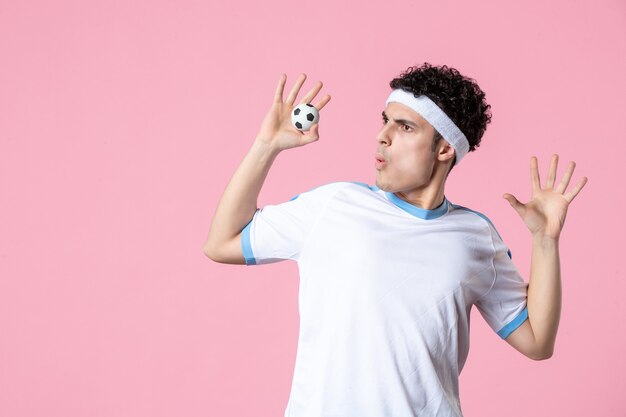 Front view soccer player in sport clothes with little ball