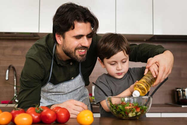 Front view son helping dad to make salad