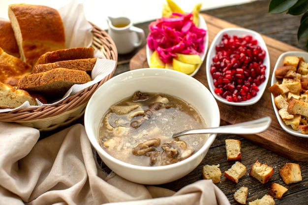 A front view soup meat tasty along with peeled out pomegranate dried bread slices on the brown wooden rustic surface