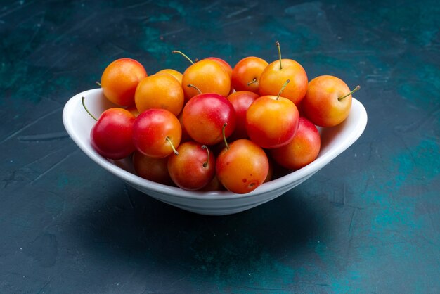 Front view of sour plums inside plate on the dark-blue surface