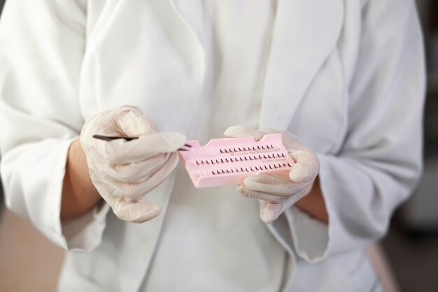 Front view specialist holding eyelashes and tweezers