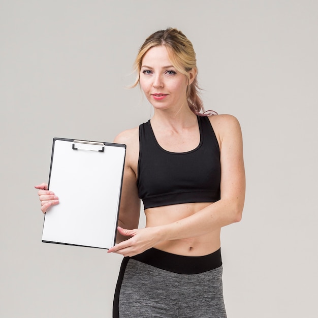 Free photo front view of sporty woman posing while holding notepad