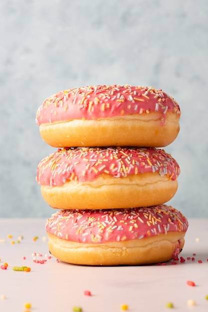 Front view of stack of doughnuts with colorful sprinkles and glazing