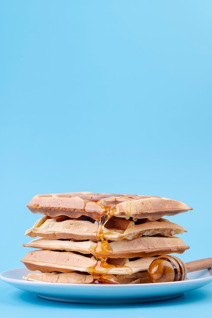 Front view of stack of waffles covered in honey with copy space