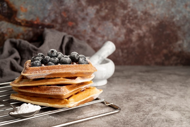 Front view of stack of waffles with blueberries and powdered sugar
