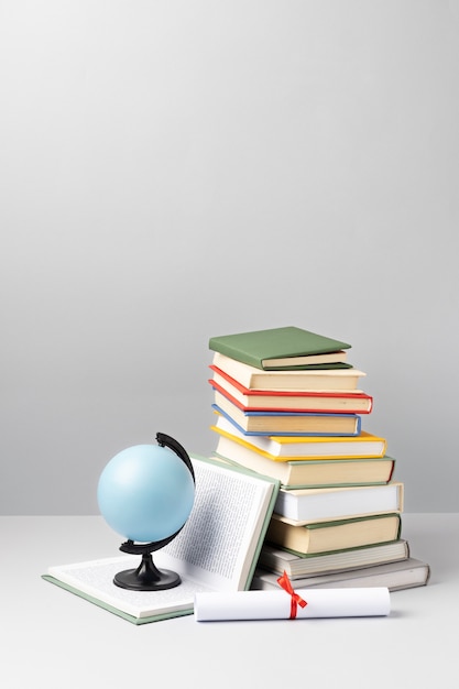 Front view of stacked books, a diploma and an earth globe with copy space for education day