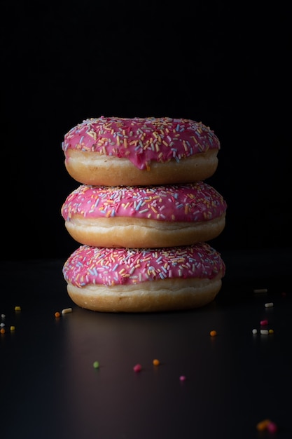 Front view of stacked glazed doughnuts with colorful sprinkles