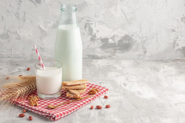 Front view of stick shaped candy in glass cup and pastries peanuts on red stripped towel on the right side on gray background