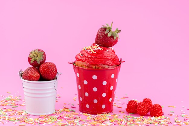 Клубничный торт, вид спереди внутри красной корзины вместе со свежей красной клубникой на розовом столе, бисквитный торт, кондитерский сахар