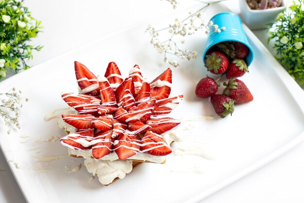 A front view strawberry cake with custard and sliced red strawberries along with fresh whole strawberries inside white desk fruit berry sugar