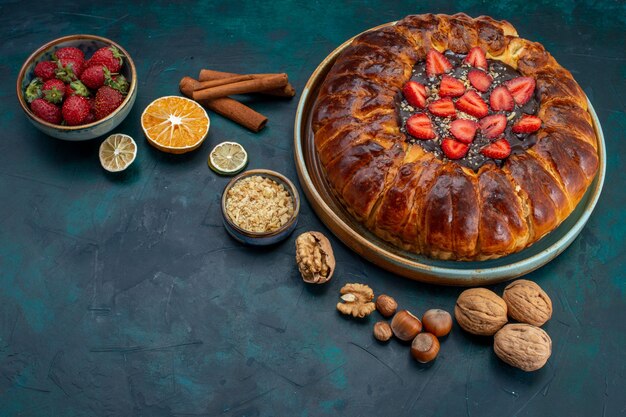 Front view of strawberry pie with nuts and cinnamon on dark-blue desk