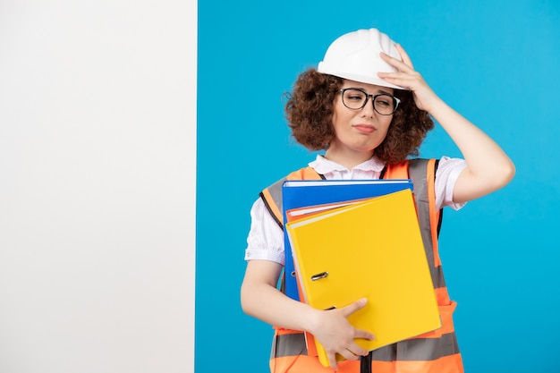 Front view stressed female builder in uniform on blue 