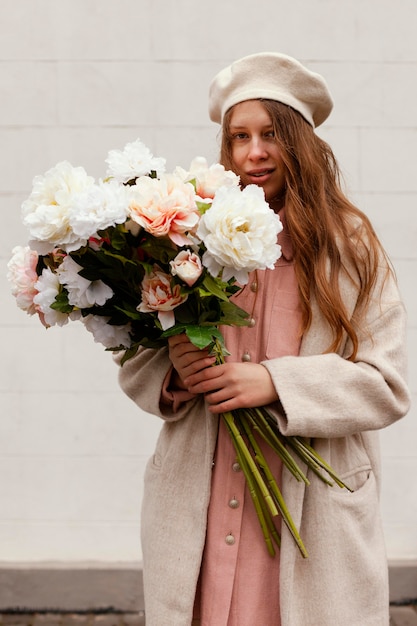 Front view of stylish woman outdoors holding bouquet of flowers in the spring