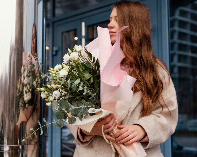 Front view of stylish woman outdoors holding a bouquet of flowers