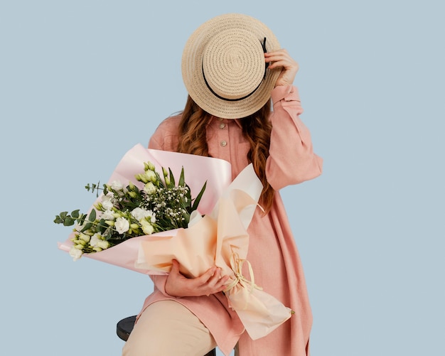 Vista frontale della donna alla moda in posa con bouquet di fiori primaverili